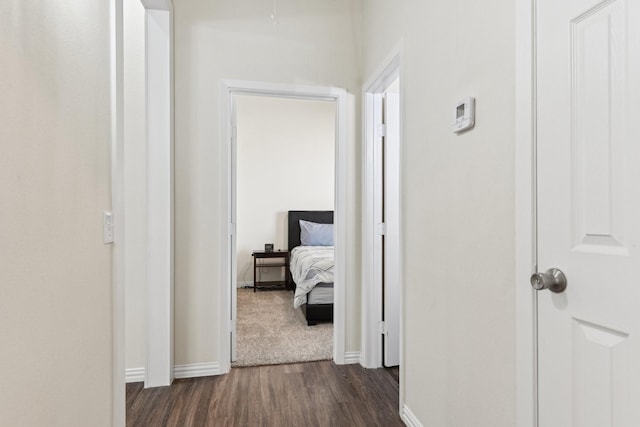 corridor featuring baseboards and dark wood-style floors