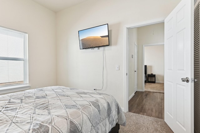 bedroom with baseboards, attic access, and wood finished floors