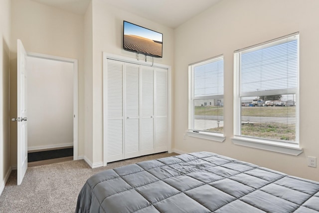 carpeted bedroom featuring a closet and baseboards