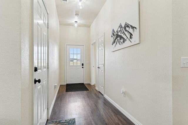 doorway with dark wood finished floors and baseboards