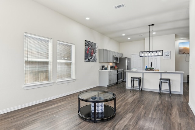 kitchen with visible vents, gray cabinets, light countertops, appliances with stainless steel finishes, and a kitchen bar