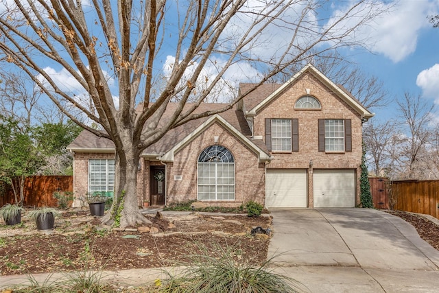 traditional-style home with brick siding, an attached garage, driveway, and fence