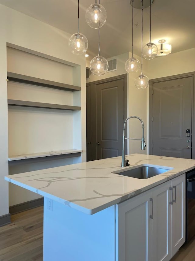 kitchen featuring light stone countertops, visible vents, open shelves, a sink, and pendant lighting