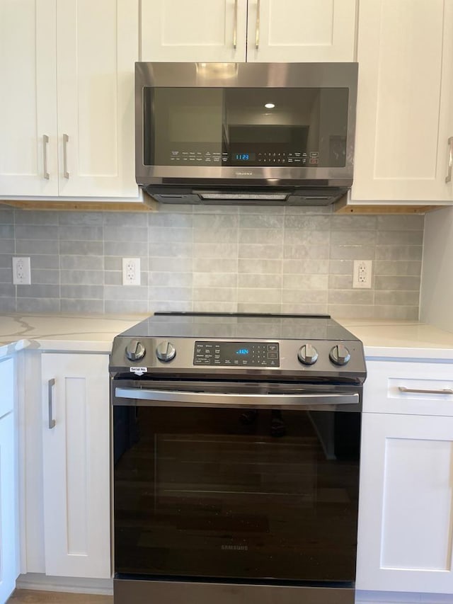 kitchen with white cabinets, tasteful backsplash, and appliances with stainless steel finishes