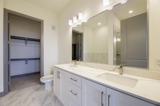 bathroom with a shower with shower door, toilet, a walk in closet, and a sink