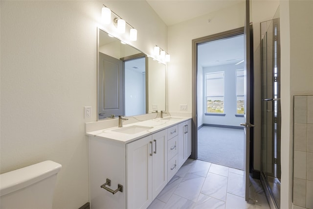 full bathroom featuring a sink, an enclosed shower, toilet, and double vanity