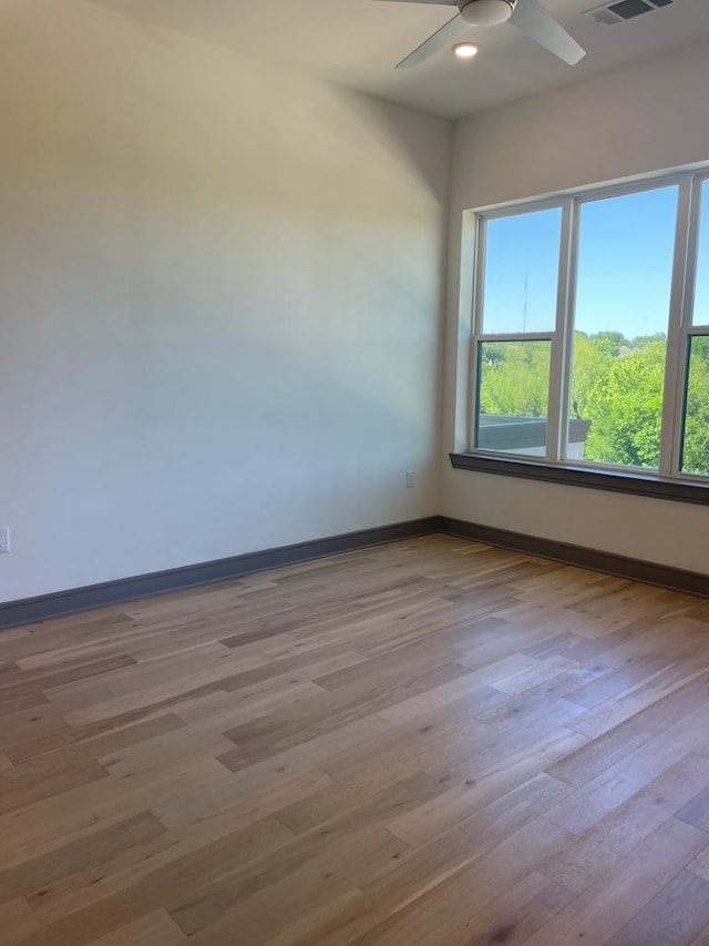 spare room featuring ceiling fan, visible vents, baseboards, and wood finished floors