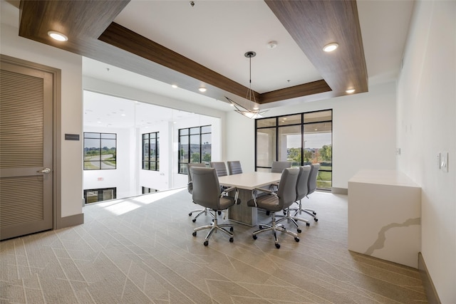 dining room with baseboards, a raised ceiling, light colored carpet, and a healthy amount of sunlight