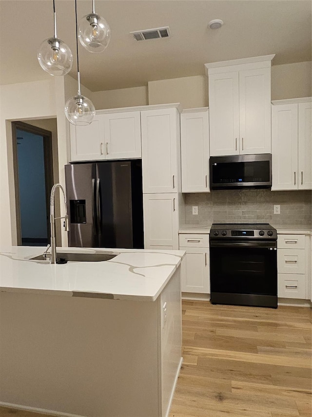 kitchen featuring visible vents, a sink, range with electric cooktop, stainless steel microwave, and refrigerator with ice dispenser