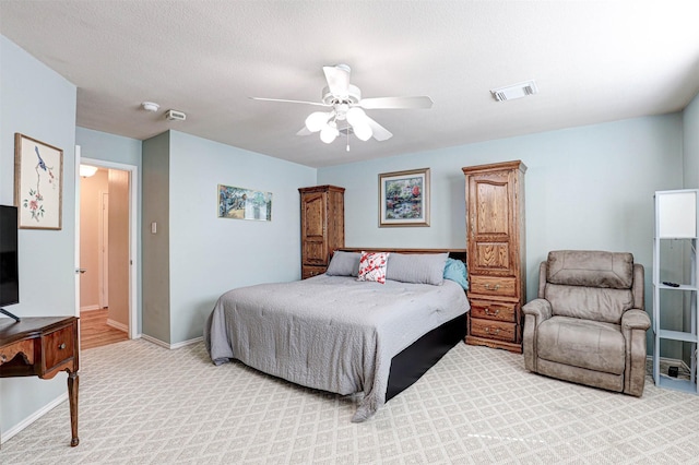 bedroom with baseboards, visible vents, ceiling fan, a textured ceiling, and light colored carpet