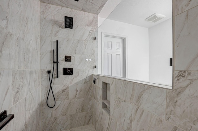 full bath with visible vents and tiled shower