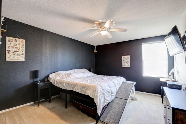 bedroom with a ceiling fan, a textured ceiling, baseboards, light colored carpet, and a textured wall