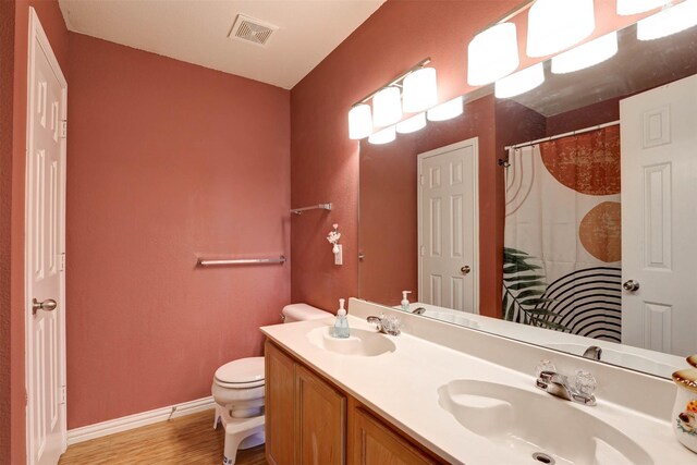 bathroom featuring visible vents, toilet, wood finished floors, and a sink