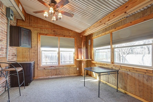 interior space with light colored carpet, ceiling fan, wooden walls, and vaulted ceiling