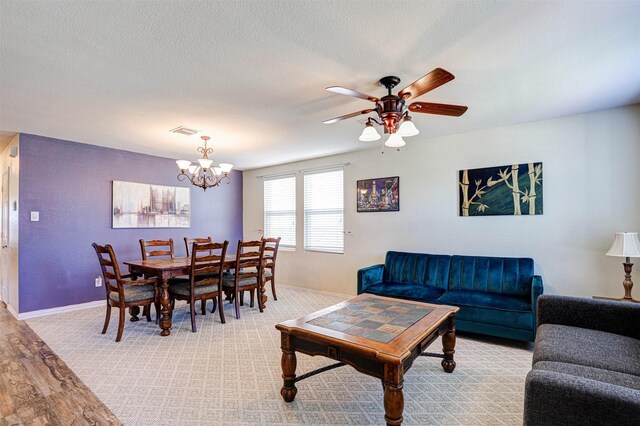 dining room with visible vents, baseboards, ceiling fan with notable chandelier, wood finished floors, and a textured ceiling