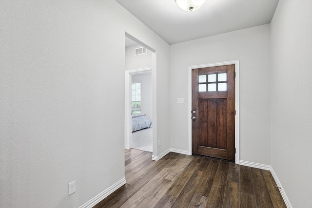 entryway with visible vents, baseboards, and dark wood-type flooring