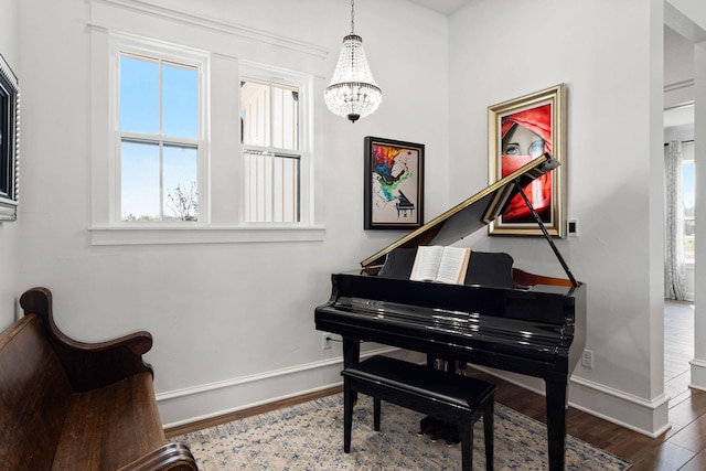 sitting room with a notable chandelier, wood finished floors, and baseboards