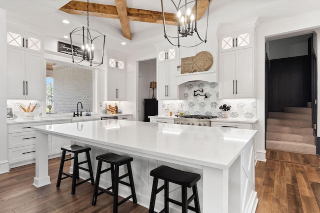 kitchen with coffered ceiling, dark wood finished floors, stove, light countertops, and beamed ceiling