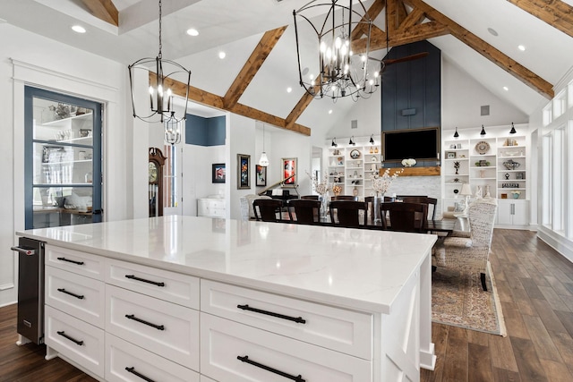 kitchen featuring light stone counters, beam ceiling, dark wood-style flooring, white cabinetry, and a notable chandelier