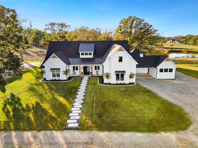 modern farmhouse with board and batten siding, gravel driveway, a front lawn, metal roof, and a standing seam roof