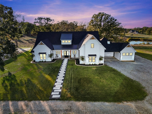 modern inspired farmhouse featuring metal roof, a lawn, gravel driveway, and a standing seam roof