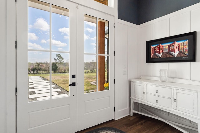 doorway to outside with dark wood-style floors, a decorative wall, and french doors