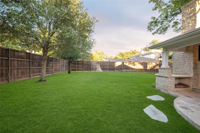 yard at dusk featuring a fenced backyard