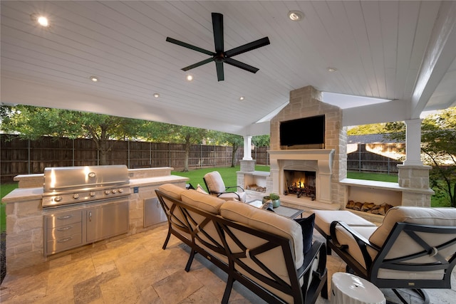 view of patio / terrace featuring a ceiling fan, an outdoor kitchen, an outdoor living space with a fireplace, a fenced backyard, and grilling area