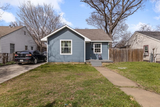 bungalow-style home featuring roof with shingles, a front yard, and fence