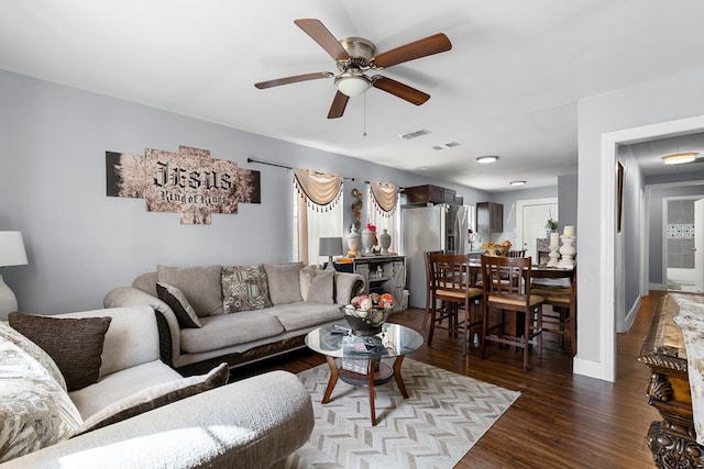 living area featuring visible vents, baseboards, wood finished floors, and a ceiling fan