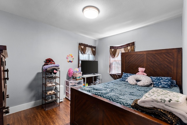 bedroom with wood finished floors, baseboards, and a textured ceiling