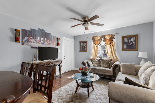 living area with baseboards, wood finished floors, and a ceiling fan