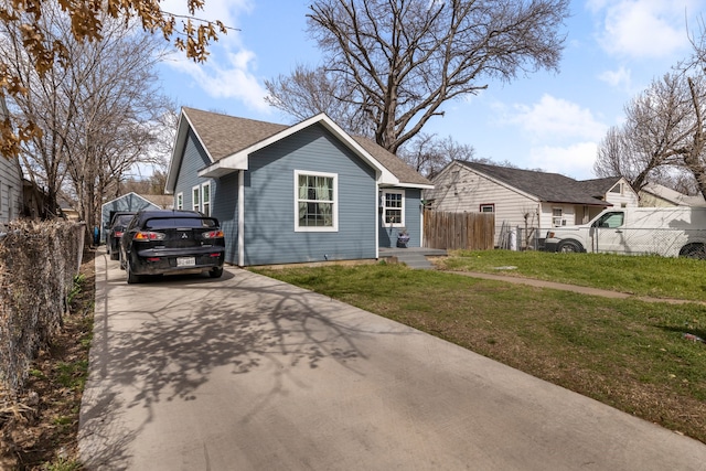 bungalow-style house featuring a shingled roof, a front lawn, and fence