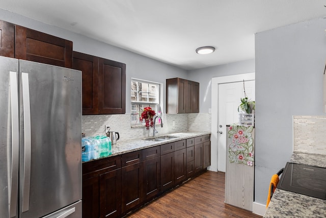 kitchen with dark wood-style flooring, tasteful backsplash, freestanding refrigerator, and a sink