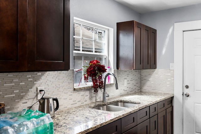 kitchen featuring dark brown cabinets, backsplash, and a sink