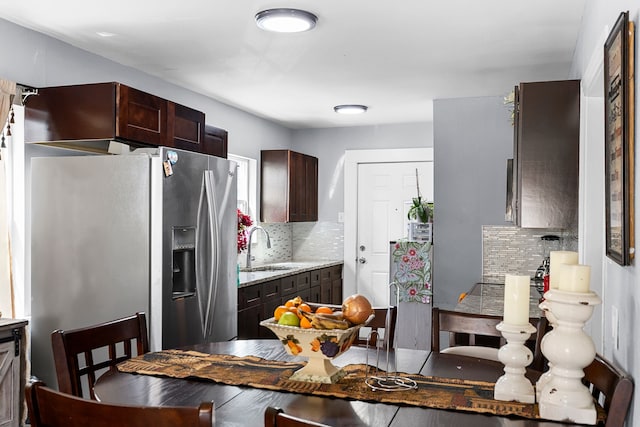 kitchen with a sink, stainless steel fridge, tasteful backsplash, and dark brown cabinetry