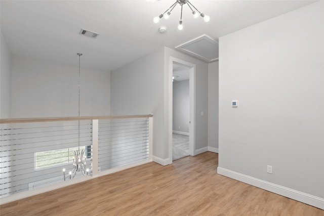 spare room with baseboards, wood finished floors, visible vents, and a chandelier