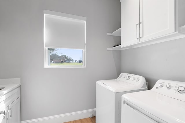 laundry area with baseboards, cabinet space, independent washer and dryer, and light wood finished floors