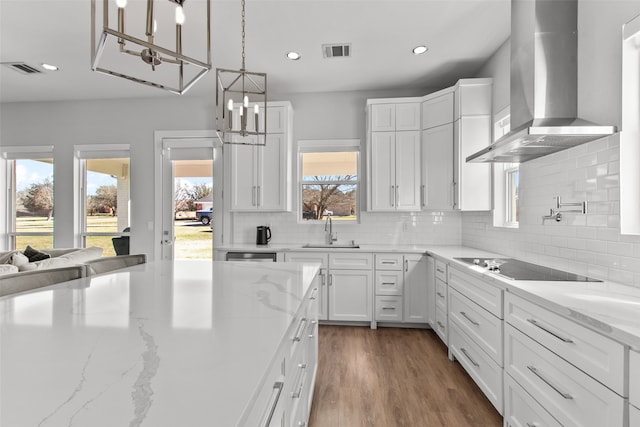 kitchen with dark wood finished floors, a sink, white cabinetry, wall chimney exhaust hood, and black electric cooktop