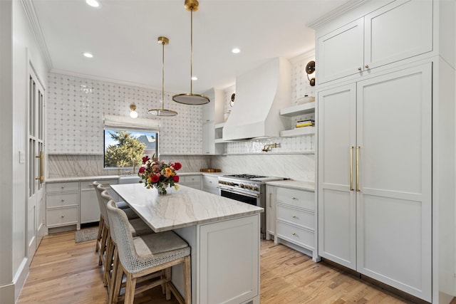 kitchen featuring light wood finished floors, open shelves, range with two ovens, custom range hood, and a center island