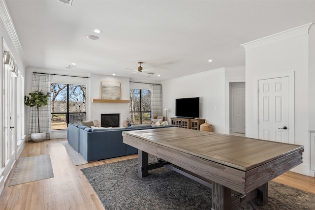 dining room featuring a ceiling fan, recessed lighting, ornamental molding, a glass covered fireplace, and light wood-type flooring