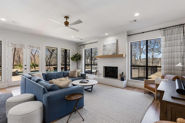 living room with visible vents, light wood finished floors, recessed lighting, ceiling fan, and a glass covered fireplace