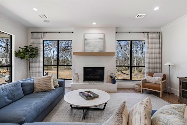 living room featuring a glass covered fireplace, recessed lighting, wood finished floors, and visible vents