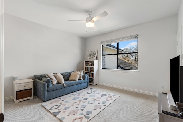 living room featuring light colored carpet, baseboards, and a ceiling fan