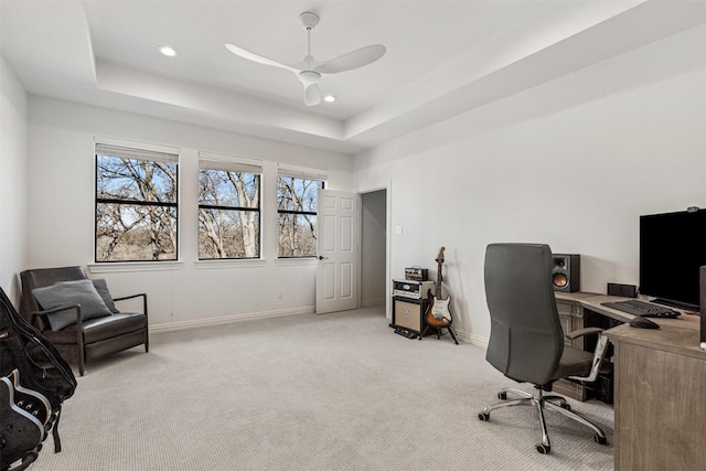 office space with baseboards, ceiling fan, light carpet, recessed lighting, and a raised ceiling