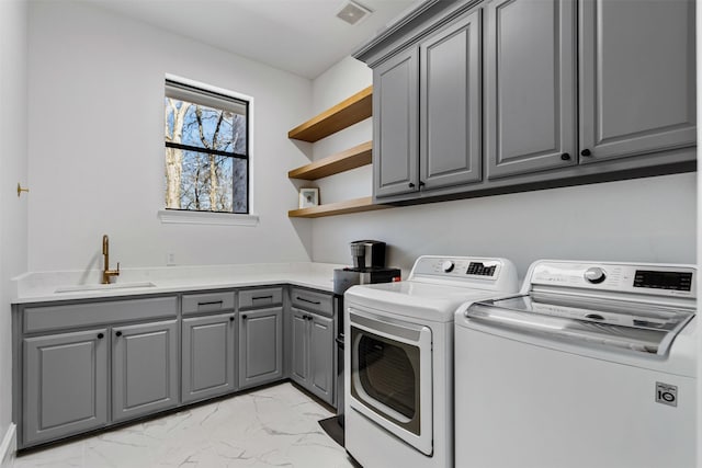 washroom with visible vents, washing machine and clothes dryer, cabinet space, a sink, and marble finish floor