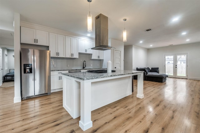 1818 Engle Ave, Dallas, TX 75224 - kitchen with stainless steel fridge, island exhaust hood, a sink, light stone counters, and light wood finished floors