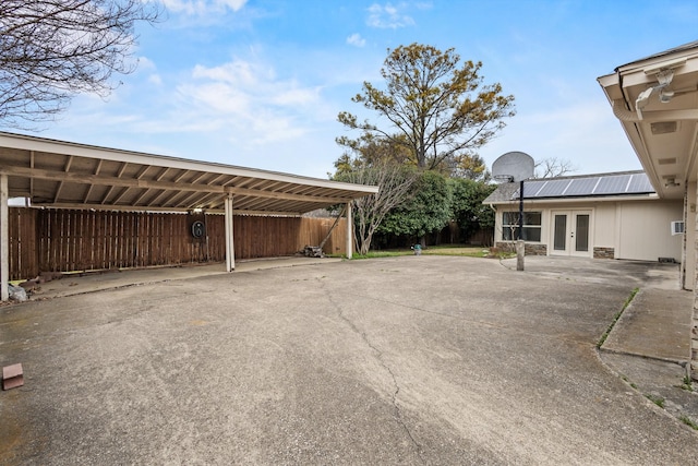 view of parking / parking lot with french doors, driveway, and fence