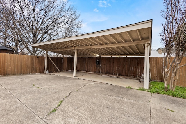 view of car parking featuring a carport, driveway, and fence