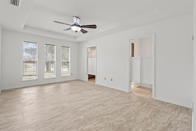 interior space with visible vents, baseboards, ensuite bathroom, and a tray ceiling